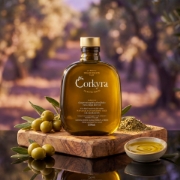 CORKYRA Selected Blend extra virgin olive oil bottle displayed on a rustic wooden board with fresh green olives and Greek herbs, set against a sun-drenched olive grove background.