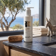 Mastic Spa Shower Gel on a dark stone bathroom counter with a Mediterranean sea view and towels.