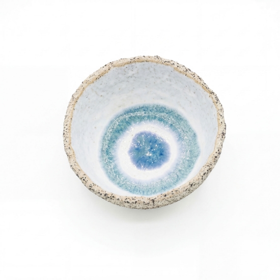 Top-down view of a handcrafted ceramic bowl with a speckled exterior and a blue concentric circle glaze inside.
