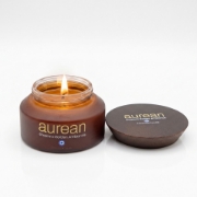 Aurean Golden scented candle in an amber glass jar with a dark wooden lid on a white background