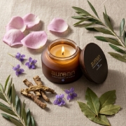 Aurean Gold Eternal Rose candle surrounded by rose petals, violets, and iris roots on a linen background